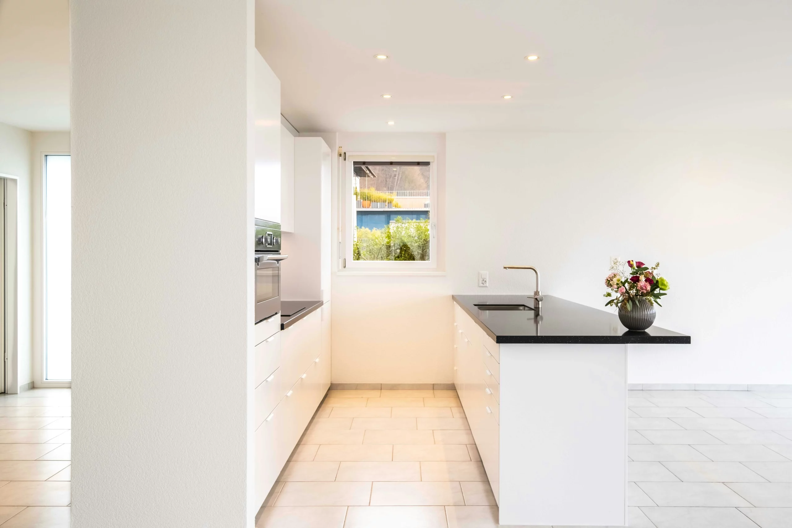 Image of a pristine white kitchen with black countertops and fresh flowers, ready for new tenants
