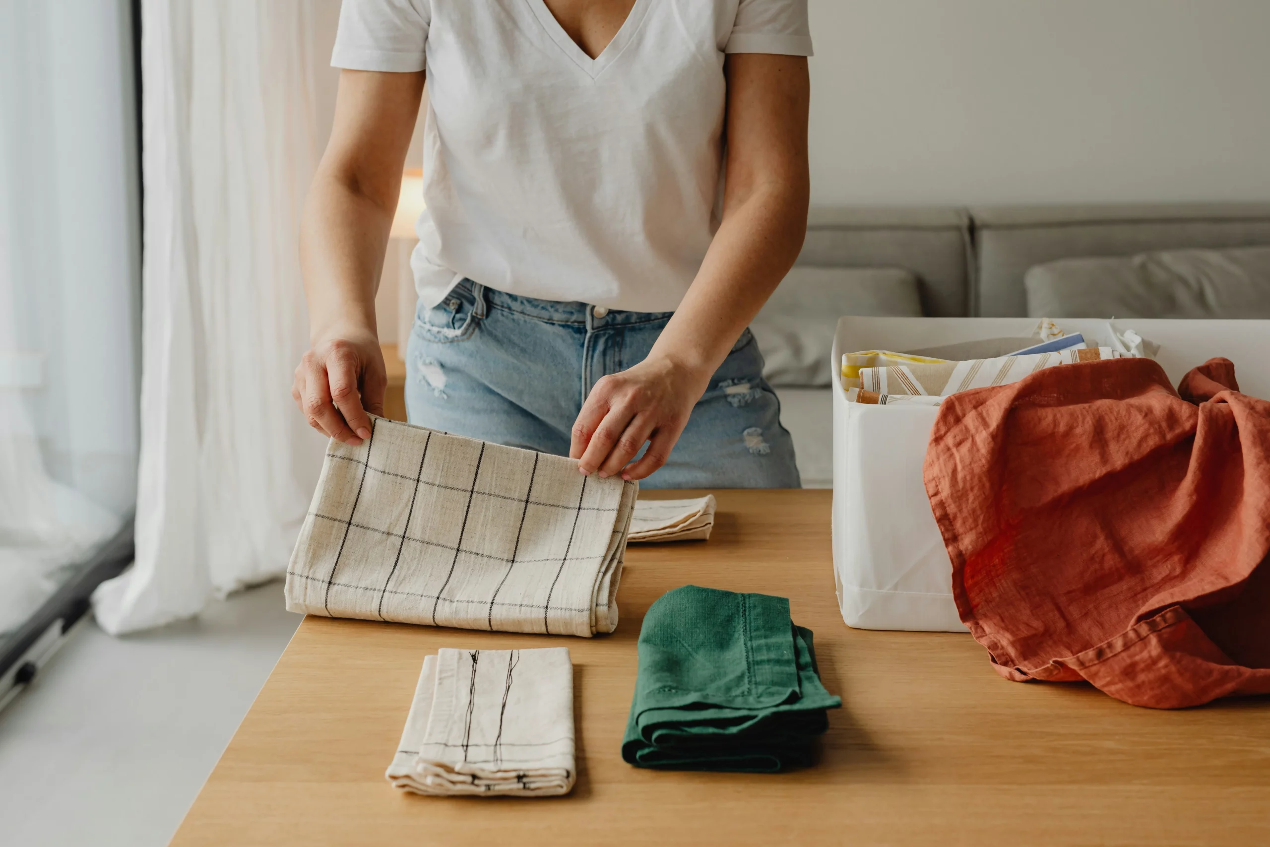 Image of a person folding linens into a white storage bin showing home organization services cost value for everyday spaces