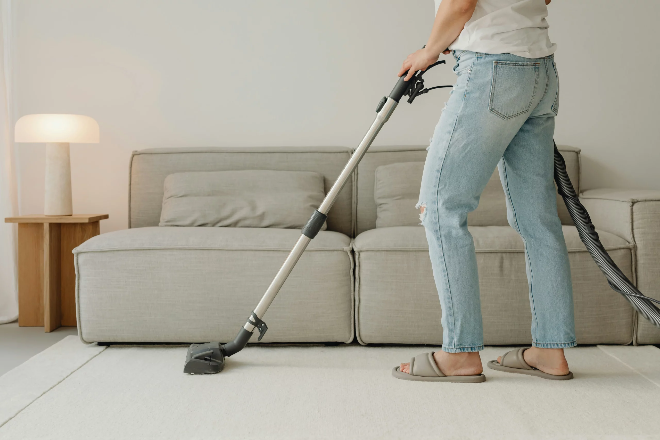 image of person vacuuming white carpet in modern living room portraying move-out cleaning cost