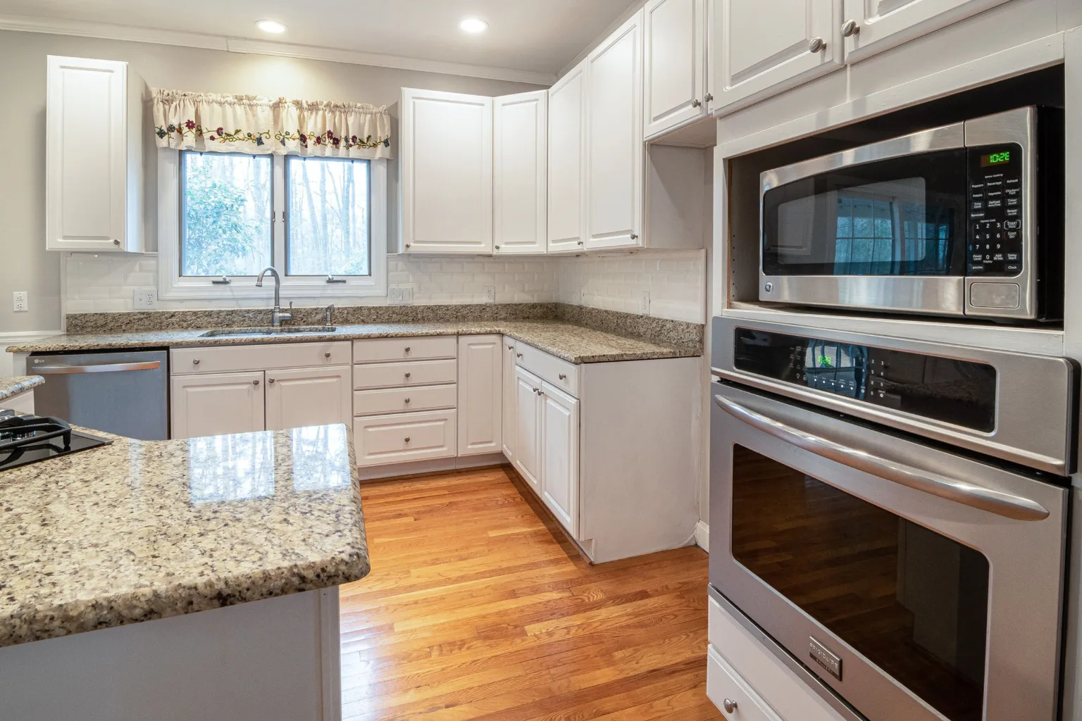 Clean white kitchen with granite counters and stainless appliances