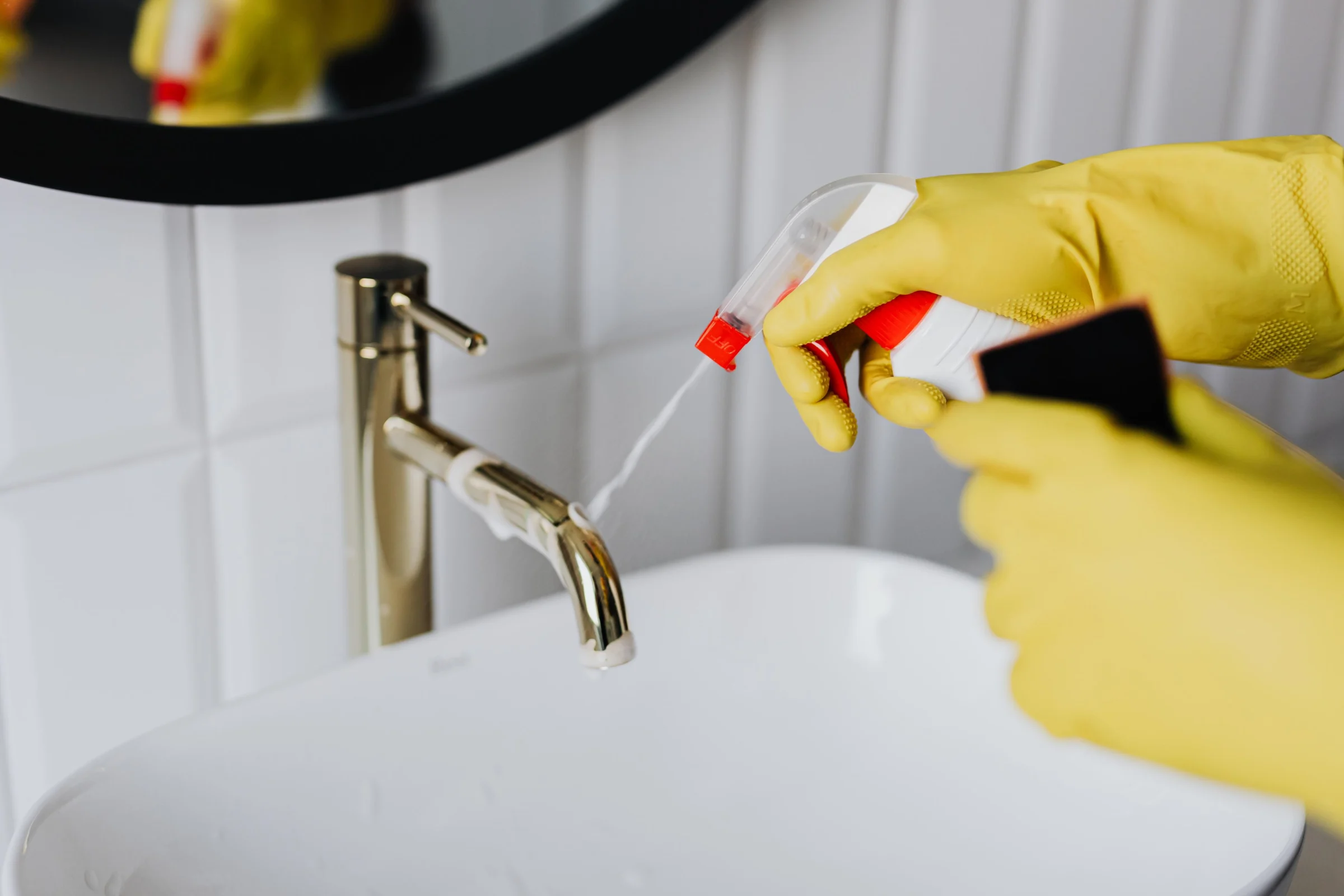 Gloved hands spraying a bathroom faucet