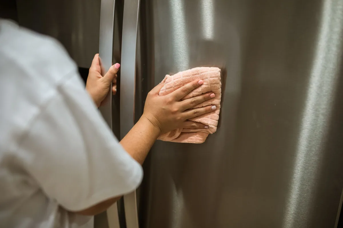 Hand wiping a stainless steel refrigerator door
