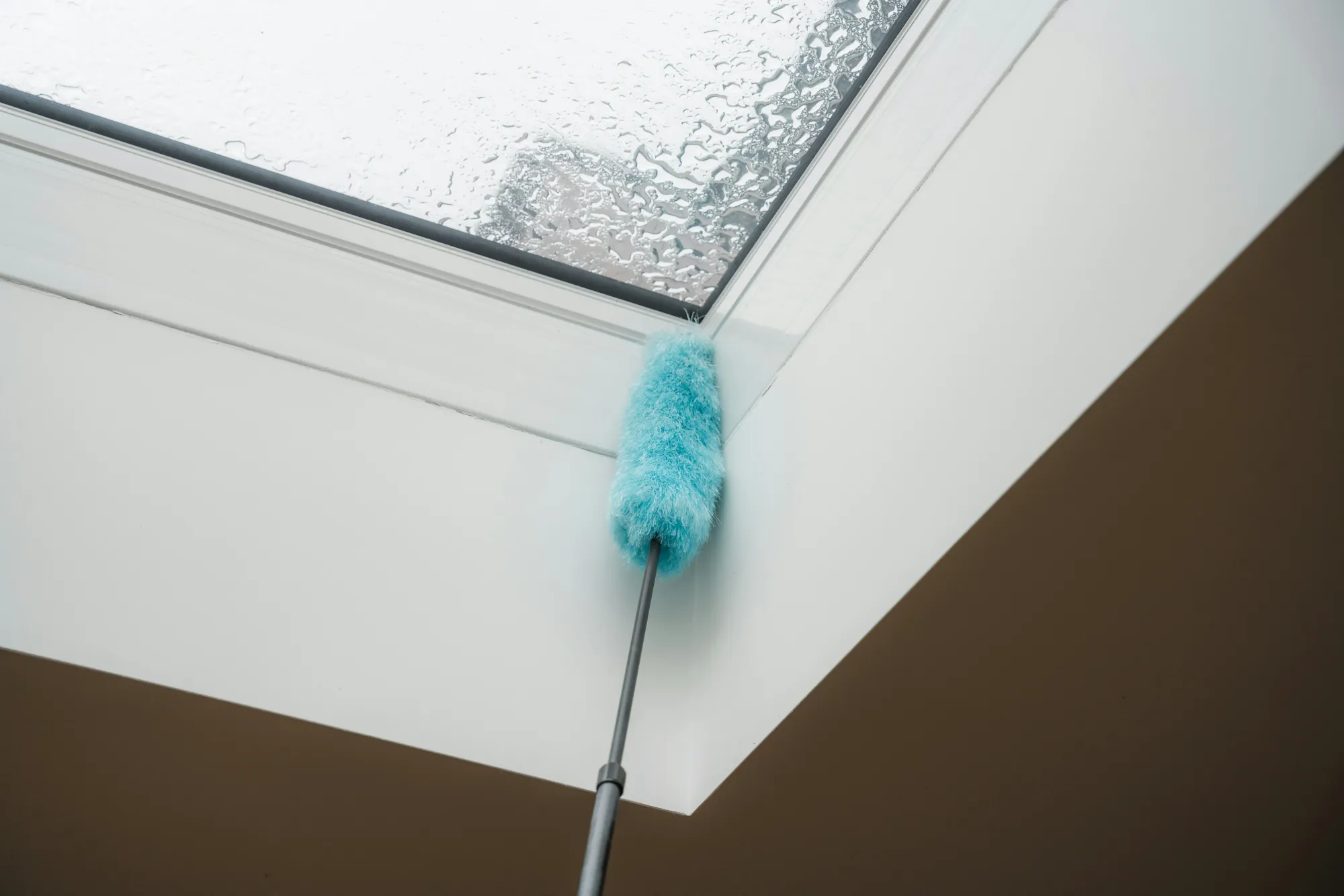 Duster cleaning the corner of a window frame