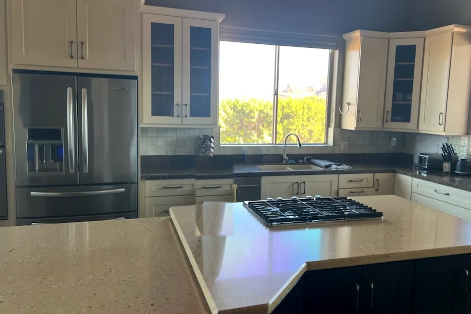 Clean kitchen with island cooktop and stainless refrigerator after a standard house cleaning in Arizona