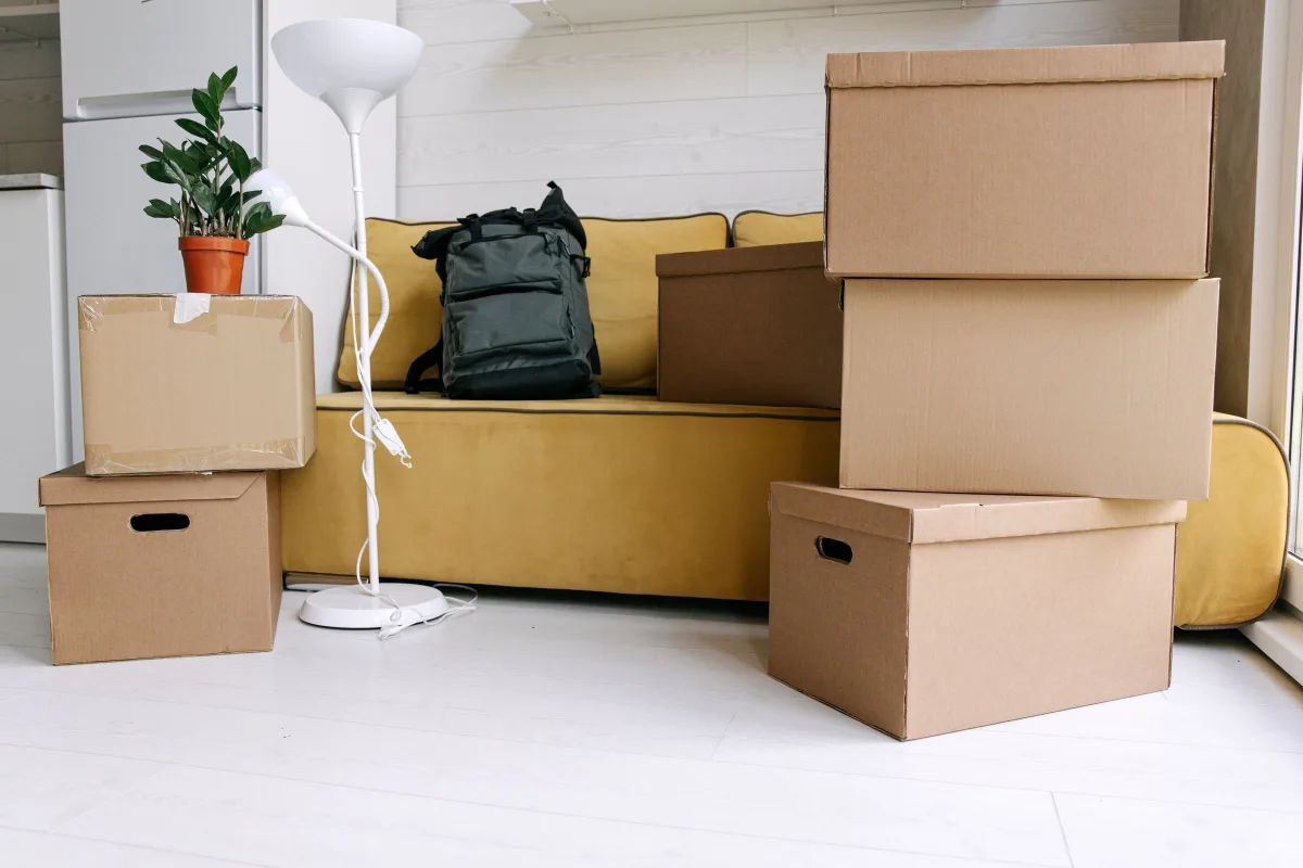 Moving boxes stacked beside a sofa in a bright room