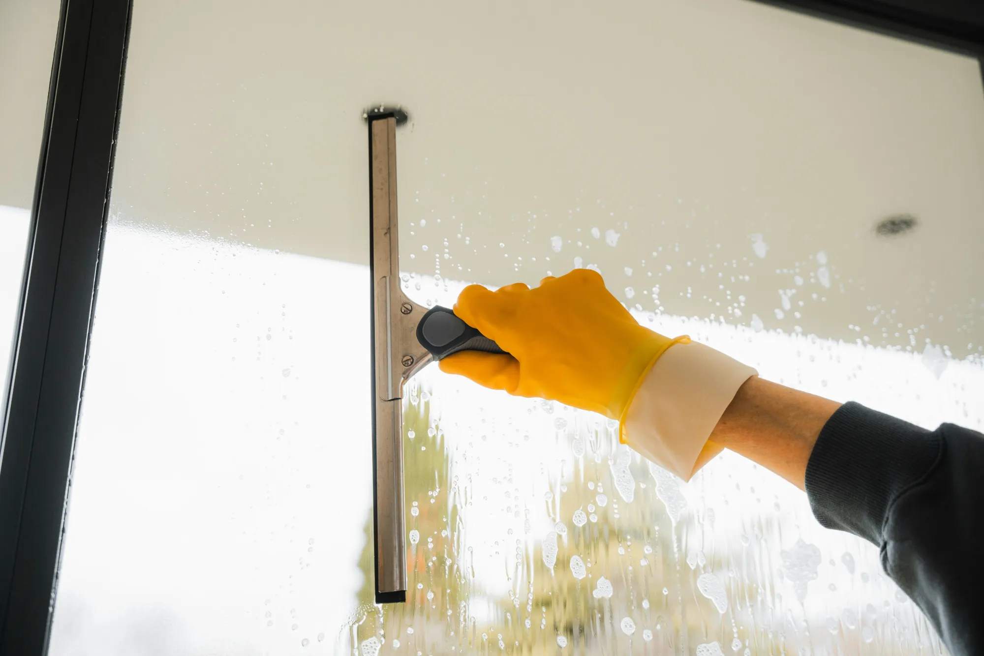 Professional cleaner washing a window, showing how much does a deep cleaning service cost for detailed home cleaning
