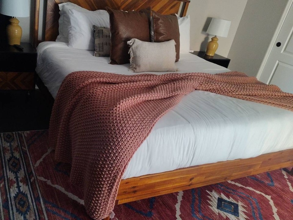 Same bed made with white linens, pillows, and a knit throw after a cleaning in Cave Creek, AZ