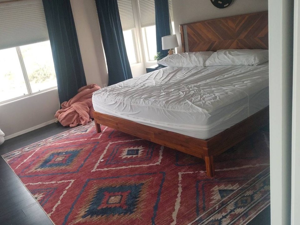 Stripped bed with bedding piled on a pouf before a cleaning in Cave Creek, AZ