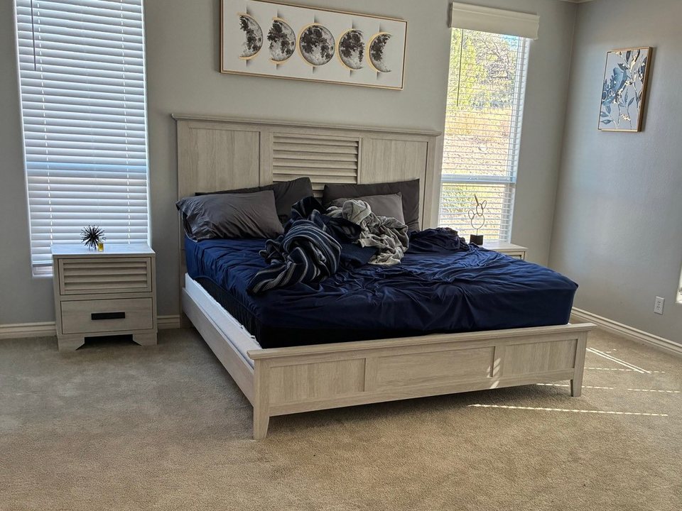 Unmade king bed with crumpled sheets in a bright bedroom before a cleaning in Williams, AZ