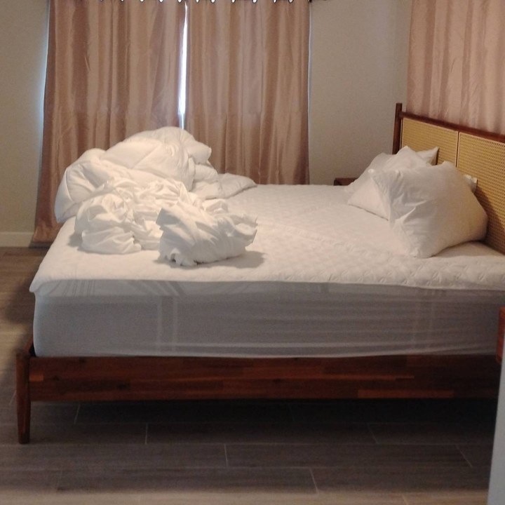 Bed stripped down with used linens piled on top before cleaning in Scottsdale, AZ