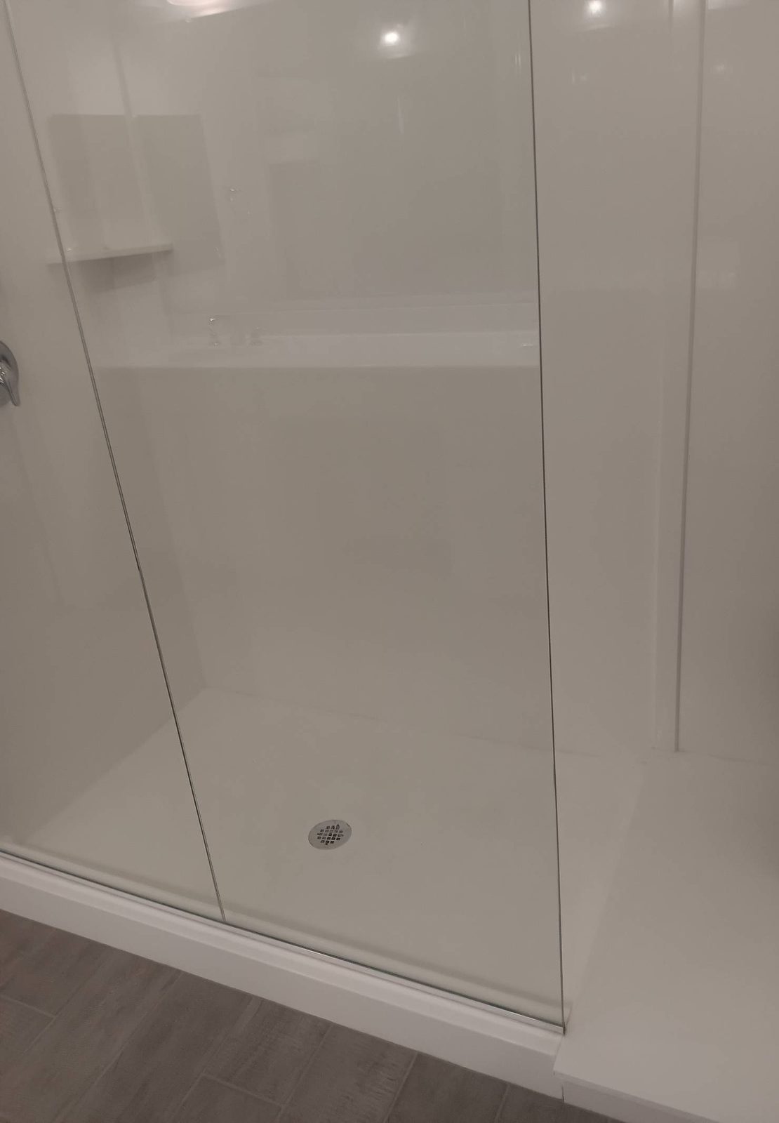 Clean white walk-in shower with a glass panel after a house cleaning in Buckeye, AZ