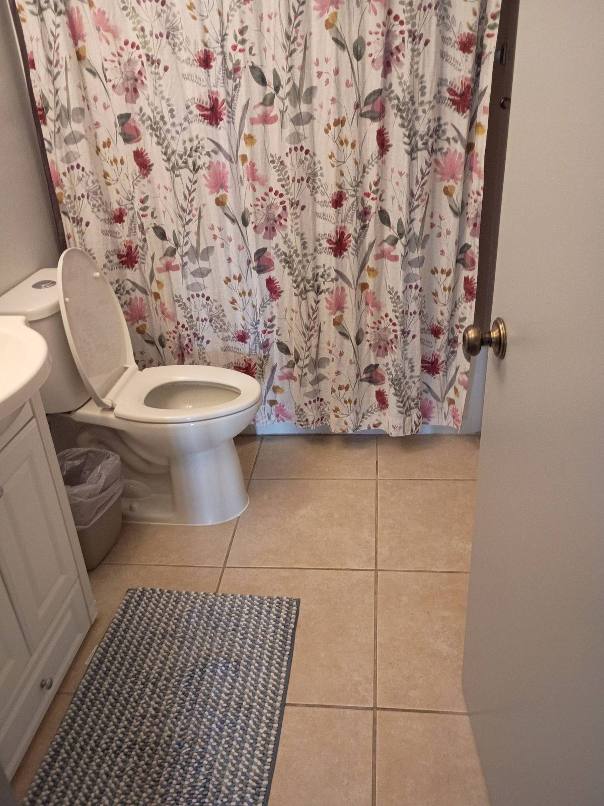 Clean bathroom with a floral shower curtain, toilet, and tile floor after a house cleaning in Carefree, AZ