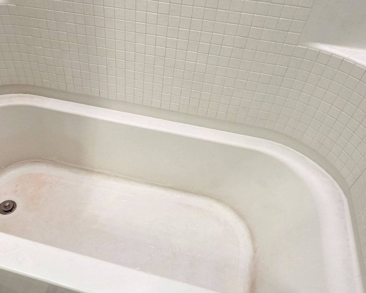 Bathtub with pink stains and soap scum before a cleaning in Casa Grande, AZ