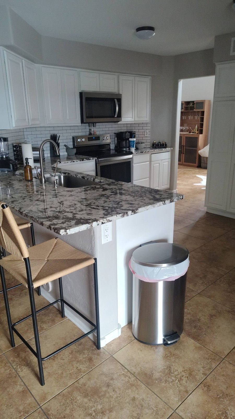 Clean kitchen with white cabinets, a granite island, and tile floor after a house cleaning in Cave Creek, AZ