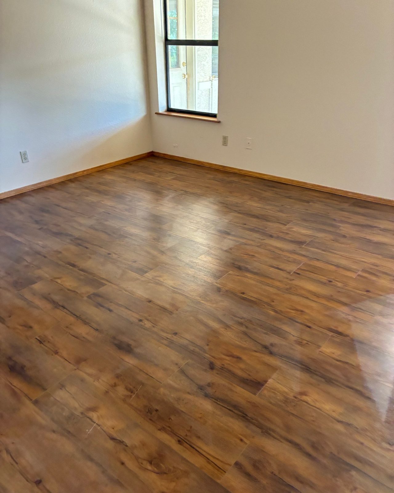 Empty room with a shiny wood-look floor and clean baseboards after a cleaning in Cottonwood, AZ
