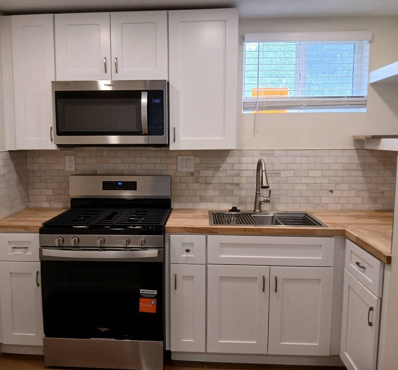 Clean kitchen with white cabinets, butcher block counters and a gas range after a cleaning in Flagstaff, AZ