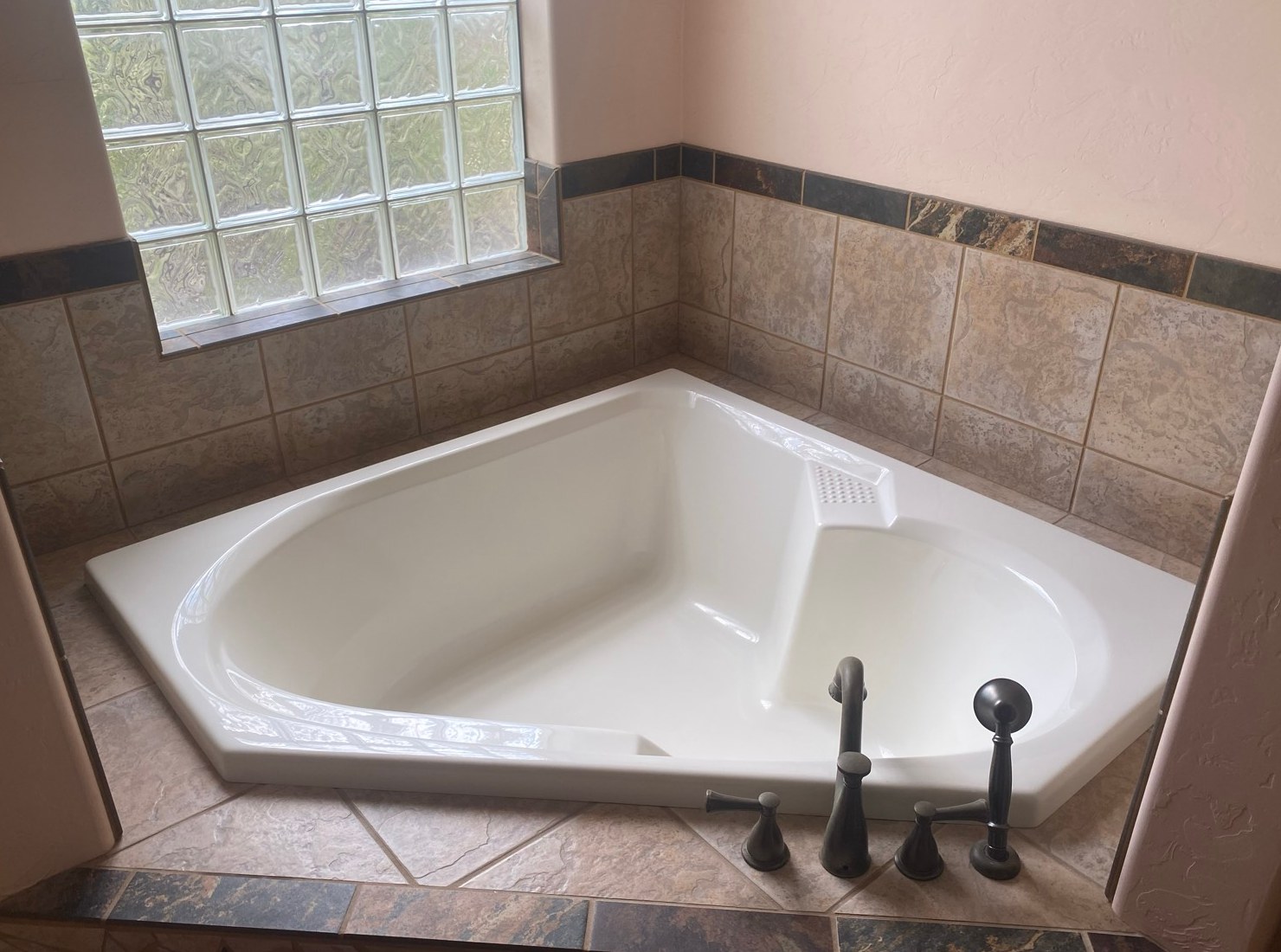Clean white corner bathtub with tile surround and dark faucet fixtures after a cleaning in Hereford, AZ
