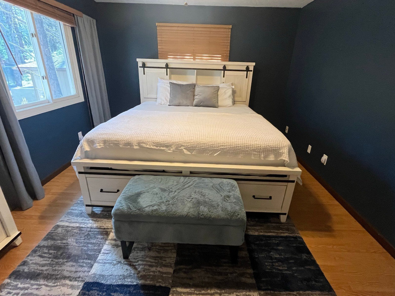Neatly made king bed with white bedding and a clean wood floor in a bedroom in Flagstaff, AZ
