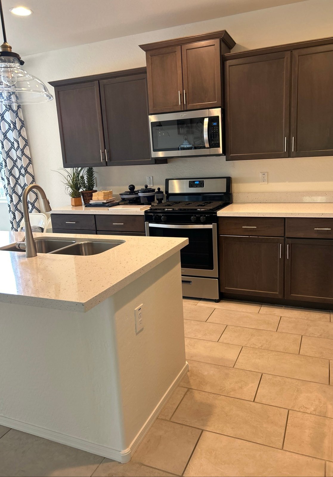 Clean kitchen with dark cabinets, light countertops, stainless steel appliances and a tile floor after a cleaning in Maricopa, AZ