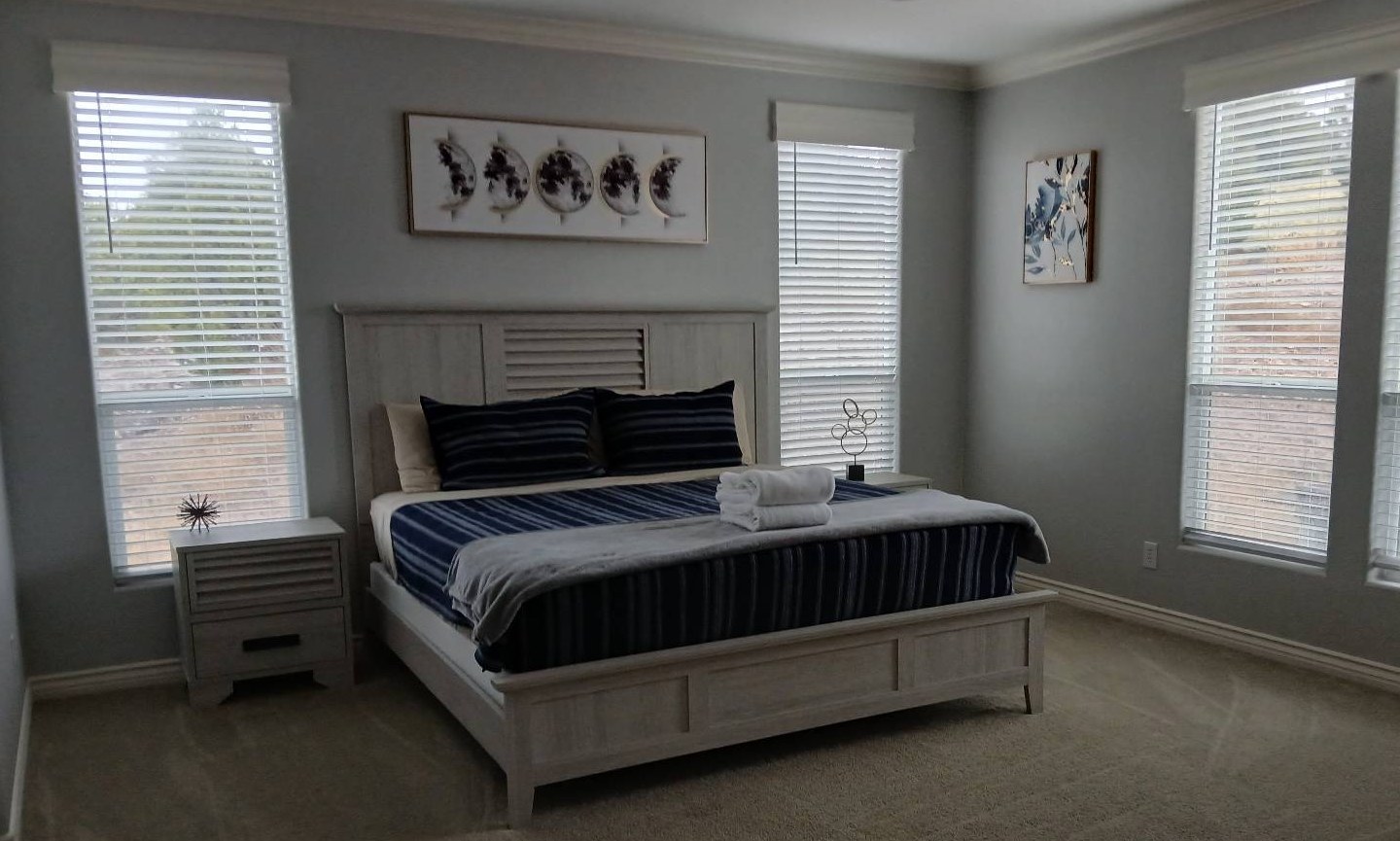 Made king bed with navy and gray bedding in a clean bedroom after a cleaning in Williams, AZ