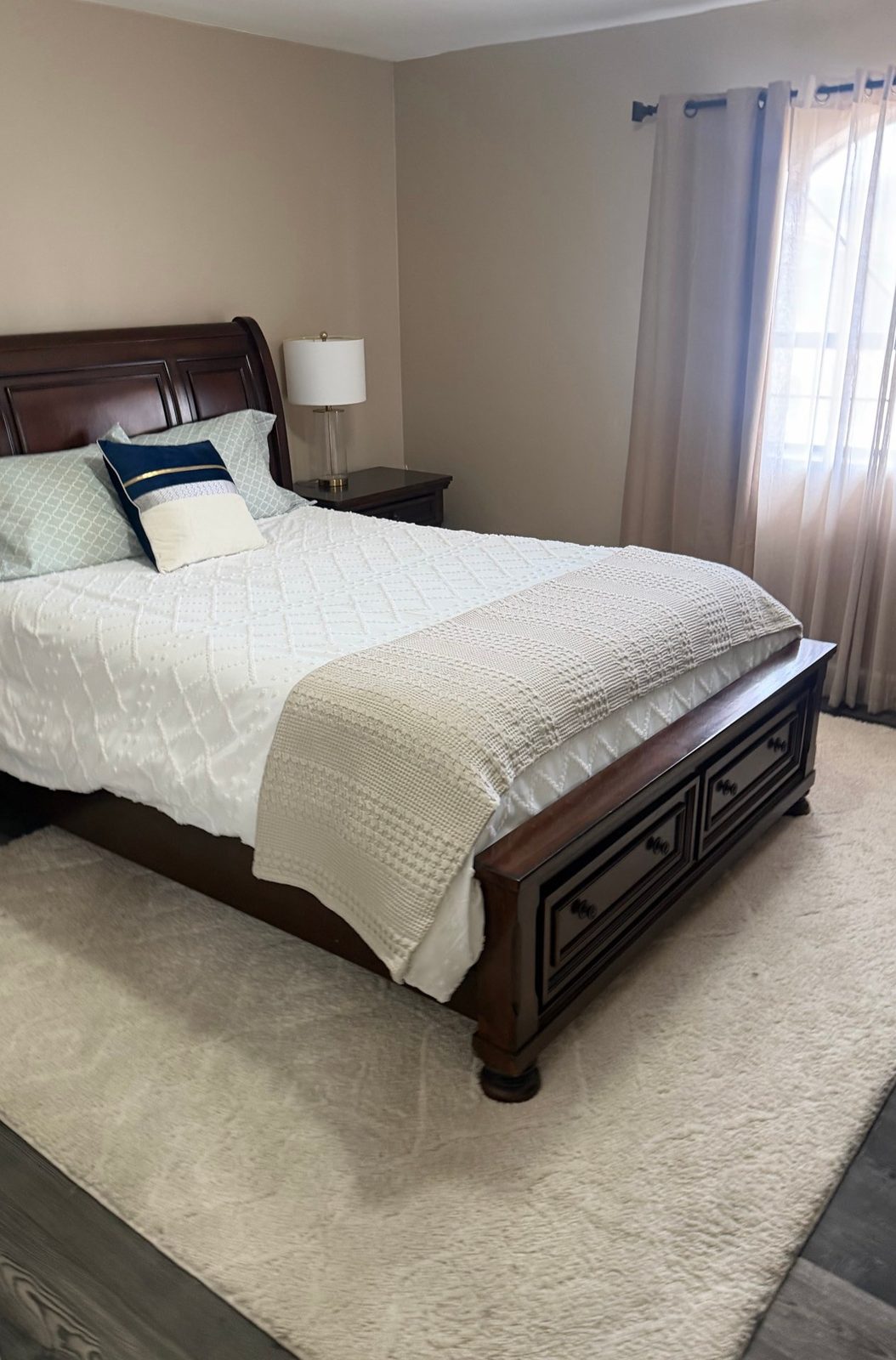 Tidy bedroom with a made bed, cream rug and sheer curtains after a cleaning in Kingman, AZ