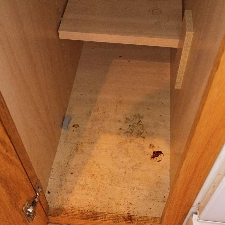 Kitchen cabinet floor with dark stains and crumbs before a cleaning in Sedona, AZ