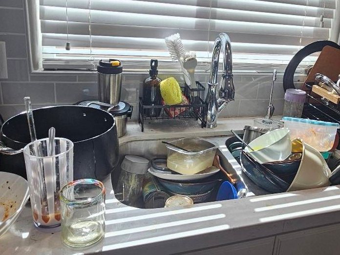 Kitchen sink piled with dirty dishes before a cleaning in Yuma, AZ