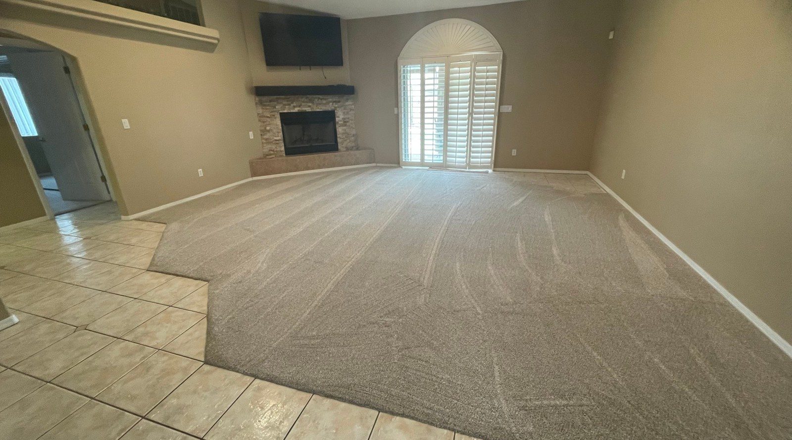 Empty living room with freshly vacuumed carpet and a stone fireplace after a cleaning in Lake Havasu City, AZ