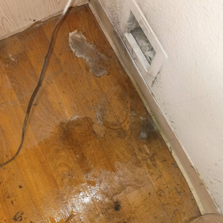 Laundry closet floor with grime, lint, and water stains before cleaning in Mesa, AZ