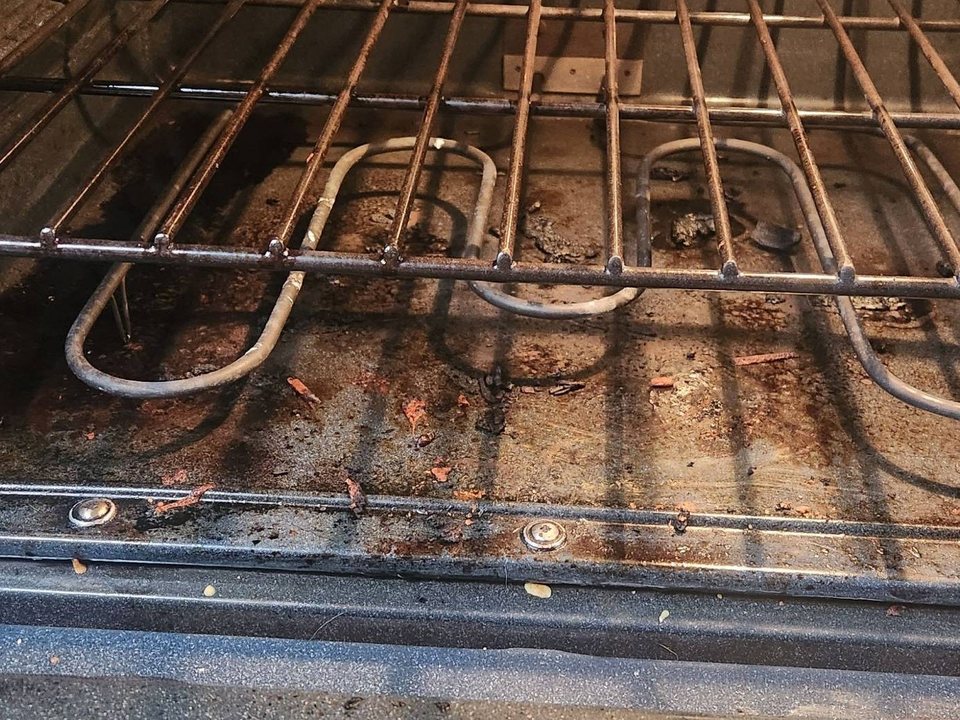Oven floor, bake element, and rack coated in burnt grease and food debris before a cleaning in Tucson, AZ