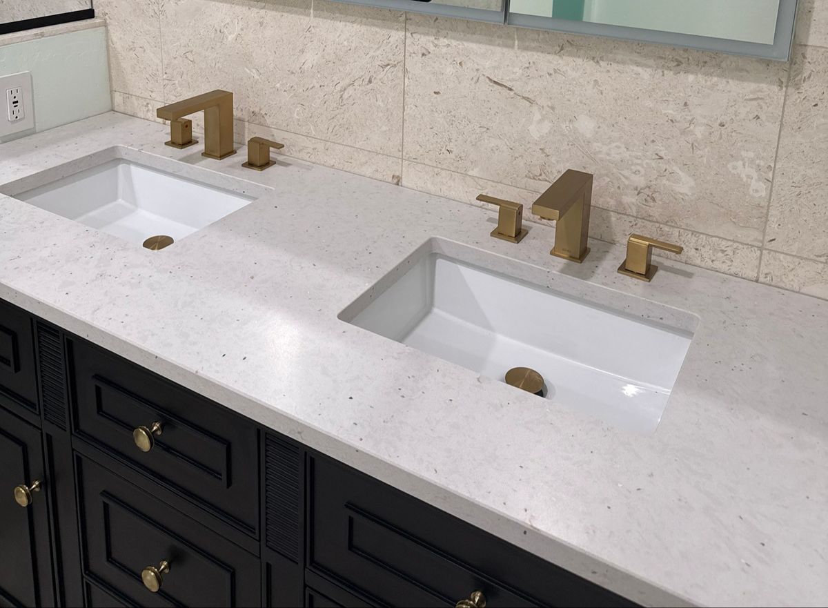 Clean double bathroom vanity with white sinks and gold faucets after a house cleaning in Overgaard, AZ