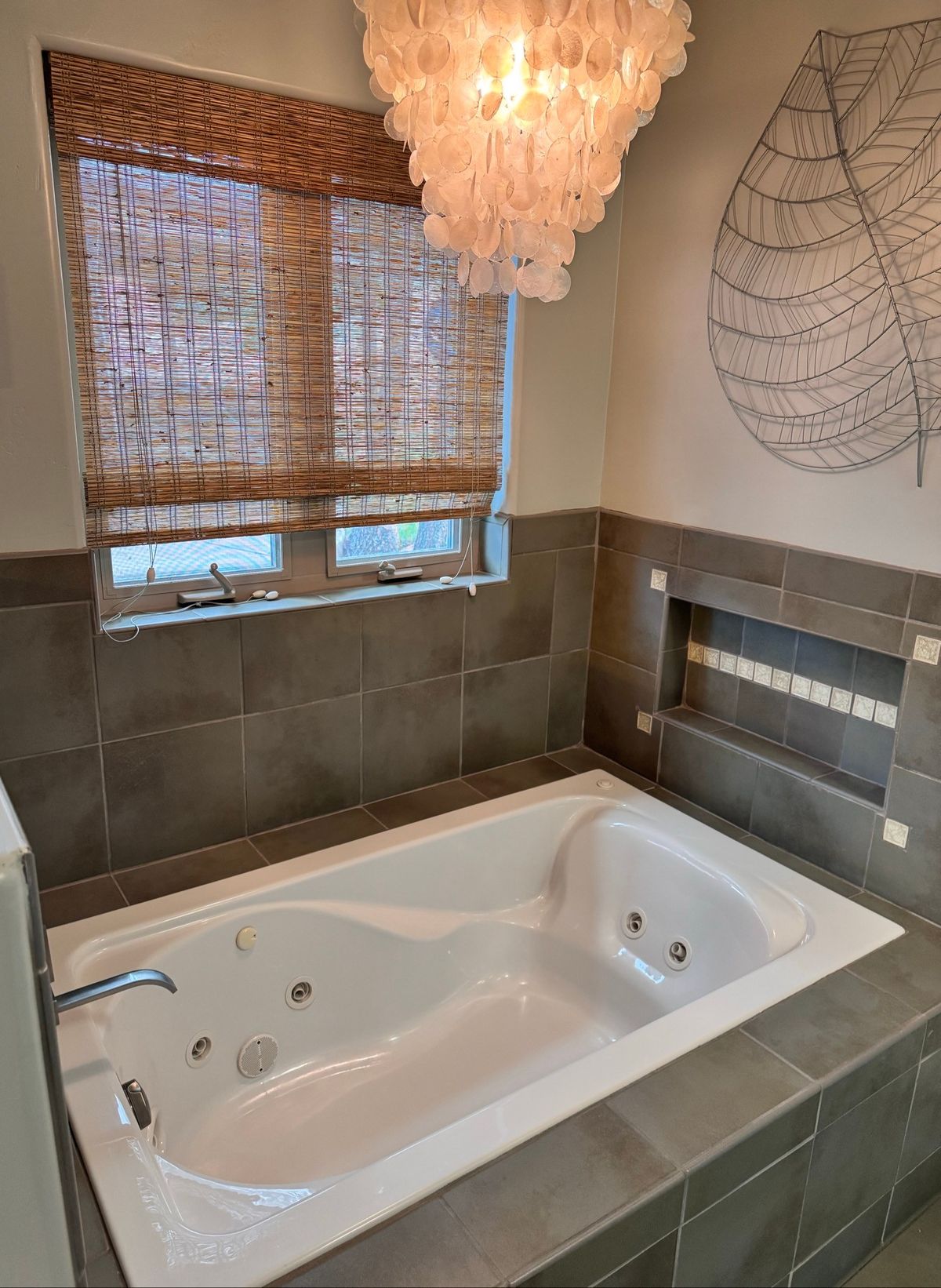 Clean jetted tub with gray tile and a shell chandelier after a cleaning in Payson, AZ