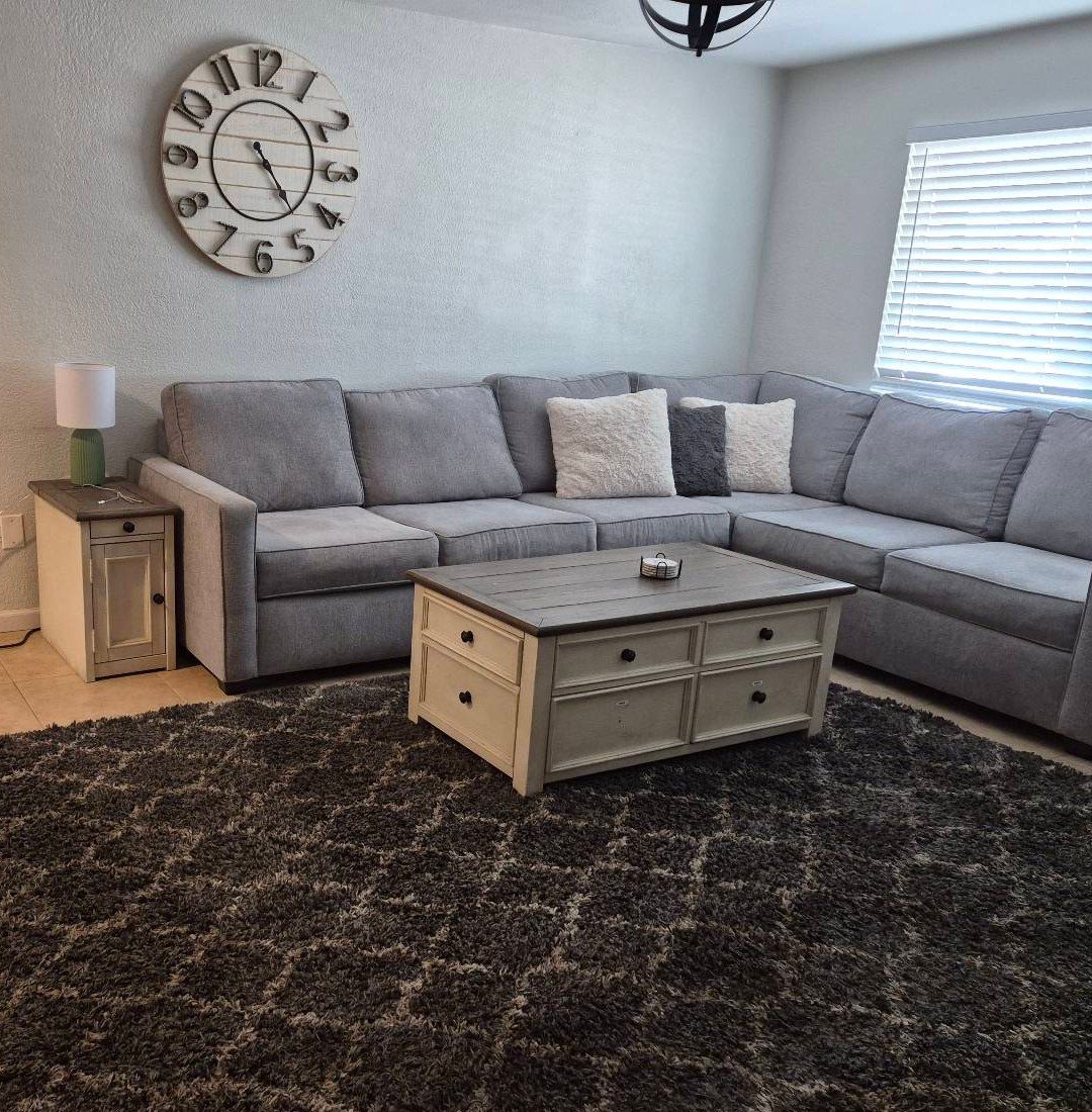 Living room with a gray sectional, white coffee table and dark shag rug after a cleaning in Phoenix, AZ