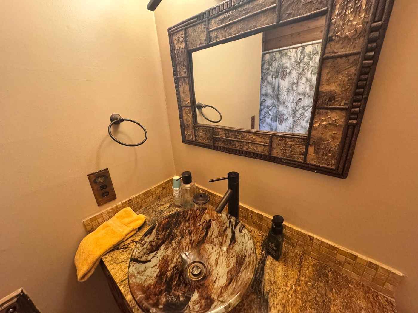 Clean powder room with a glass vessel sink and rustic mirror after a cabin cleaning in Pine, AZ