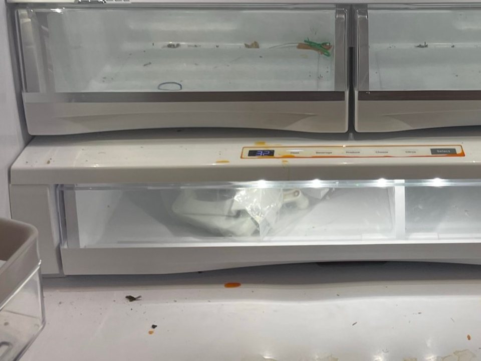 Refrigerator crisper drawers and floor with crumbs and spills before a cleaning in Phoenix, AZ
