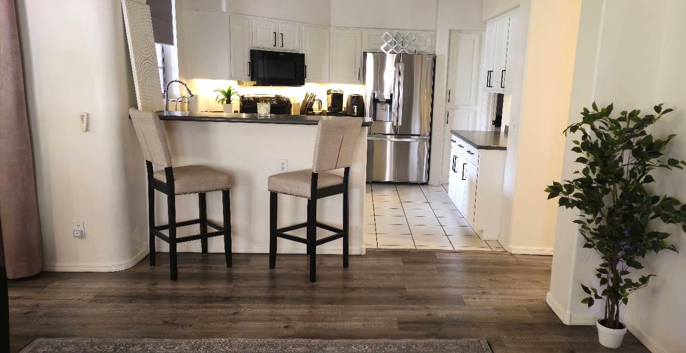 Living room and breakfast bar with white cabinets and a stainless fridge after a house cleaning in Scottsdale, AZ