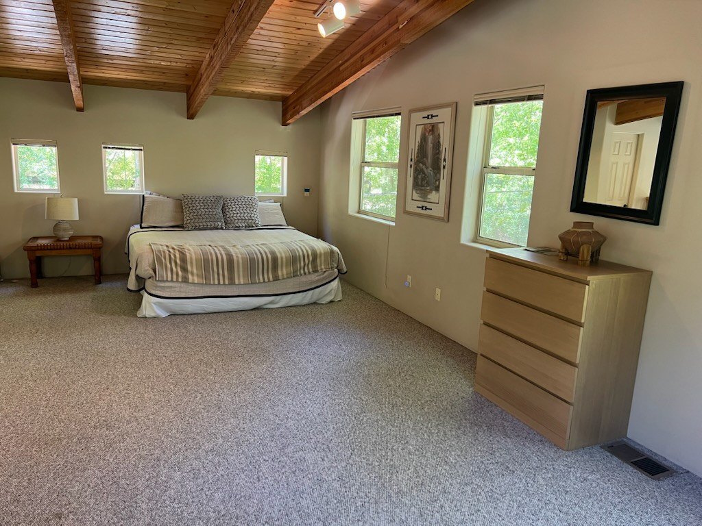 Bedroom with a beamed wood ceiling, a made bed and freshly vacuumed carpet after a post-construction cleaning in Sedona, AZ
