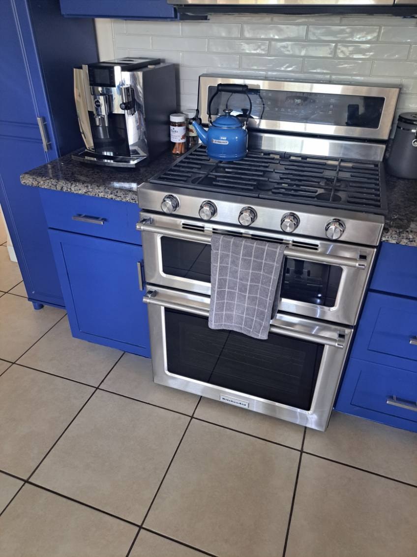 Clean kitchen with blue cabinets, a stainless gas range and tile floor after a house cleaning in Sedona, AZ