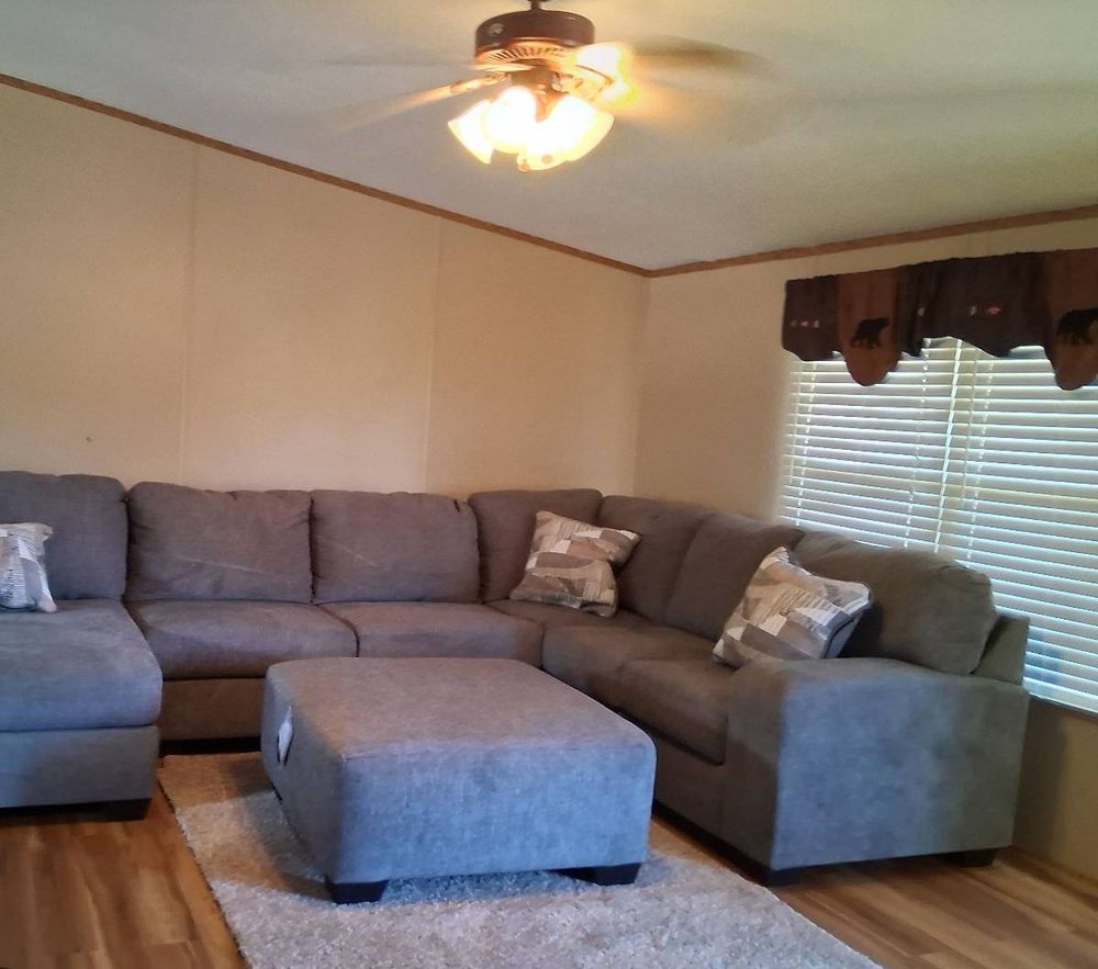 Tidy living room with a gray sectional, ottoman, shag rug, and clean floor after a cleaning in Show Low, AZ