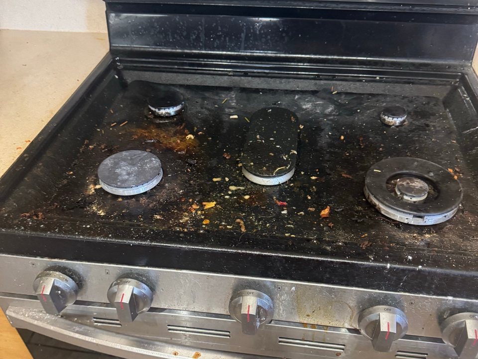 Gas cooktop covered in burnt food, crumbs, and grease before a cleaning in Sierra Vista, AZ