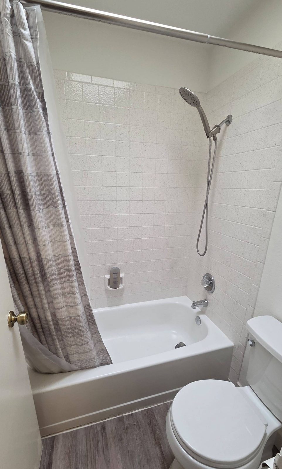Clean bathroom with a white tub, tile shower surround, and toilet in Tempe, AZ