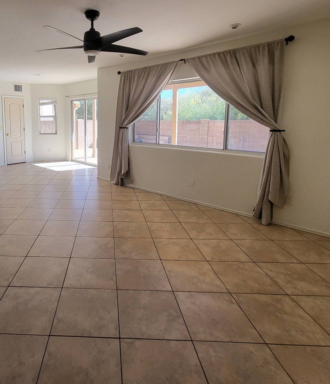 Bright open living area with clean tile floors, a ceiling fan and curtained windows after a cleaning in Tucson, AZ