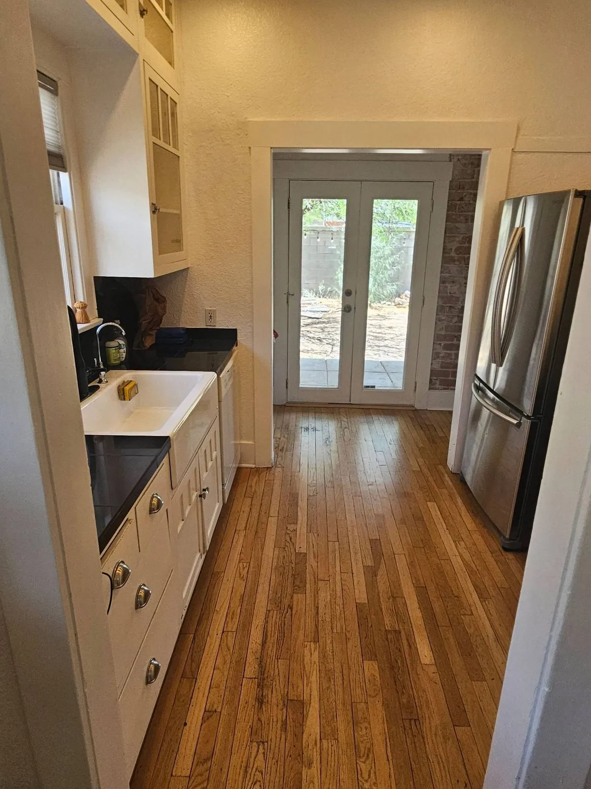 Galley kitchen with white cabinets, black counters and a clean wood floor after a house cleaning in Tucson, AZ